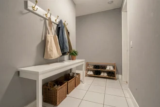 Entrée de maison bien organisée avec console murale, crochets en laiton et range-chaussures compact pour optimiser l'espace
