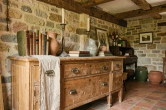 Coin brocante dans un atelier rustique avec commode en chêne, objets vintage et murs en pierre apparente